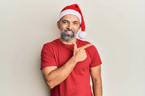 Μεσήλικας Όμορφος Άντρας Χριστουγεννιάτικο Καπέλο Και Καλοκαιρινό Μπλουζάκι Χαμογελαστός Δείχνοντας — Φωτογραφία Αρχείου