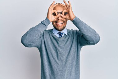 İspanyol yetişkin bir adam gözlük takıyor ve iş stili yapıyor. Dürbün gibi jest yapıyor. Dürbün dilini çıkarıyor, gözler parmaklarından bakıyor. çılgın ifade. 