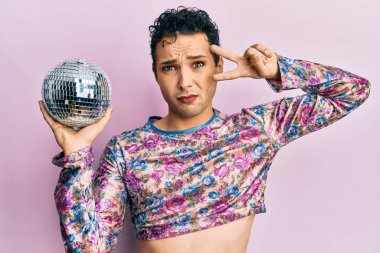Parlak disko topunu tutan yakışıklı bir adam cahil ve kafası karışmış bir ifade takınıyor. şüphe kavramı. 