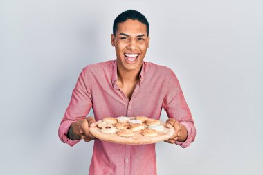 Genç Afrikalı Amerikalı çocuk elinde pasta tepsisiyle gülüyor ve kahkahalarla gülüyor.. 