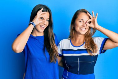 Mavi arka planda günlük giysiler giyen İspanyol anne ve kız ailesi el hareketleriyle gülümsüyor, gözleriyle mutlu yüzlere bakıyor.. 