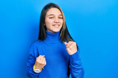 Balıkçı yaka kazak giyen genç esmer kız kolları havada ve gözleri kapalı bir şekilde başarıyı kutluyor. Kazanan konsept. 