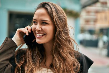 Genç İspanyol kadın şehirde akıllı telefondan konuşuyor..