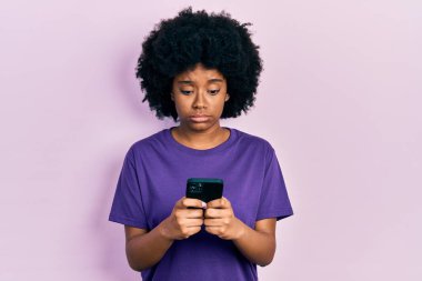 Genç Afro-Amerikalı kadın akıllı telefon kullanıyor şüpheci ve gergin mesajlar yazıyor, sorun yüzünden surat asıyor. negatif kişi. 