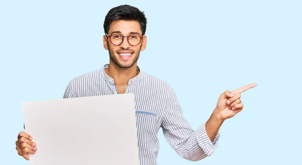 Jovem Homem Bonito Segurando Banner Vazio Branco Sorrindo Feliz Apontando — Fotografia de Stock