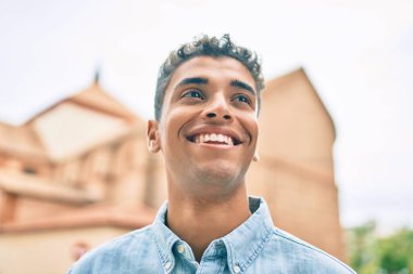 Genç Latin adam gülümseyerek şehirde mutlu mesut yürüyor..