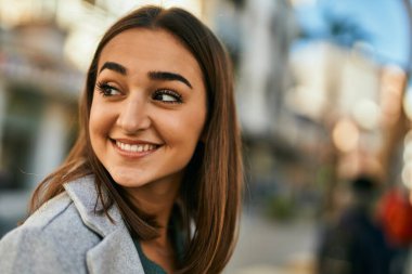 Genç İspanyol kız gülümseyerek şehirde mutlu mesut dikiliyor..