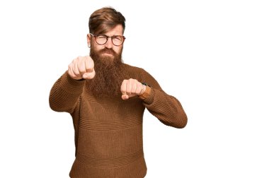 Genç İrlandalı kızıl elbiseli ve gözlüklü adam dövüşmek için yumrukluyor, agresif ve öfkeli saldırı, tehdit ve şiddet 