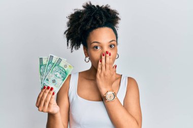 Genç Afro-Amerikalı kız elinde 100 tane Polonya zloti banknot tutuyor. Ağzını eliyle kapatıyor. Şok olmuş ve hata yapmaktan korkuyor. şaşırmış ifade 
