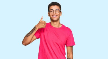 Genç, yakışıklı, Afro-Amerikalı günlük kıyafetler giyen mutlu ve pozitif gülümseyen, başparmağını kaldıran, mükemmel ve onay işareti yapan bir adam. 