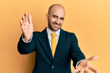 Genç İspanyol bir adam iş elbisesi ve kravat takmış kameraya bakıp sarılmak için kollarını açmış gülümsüyor. Mutluluğu kucaklayan neşeli bir ifade.. 