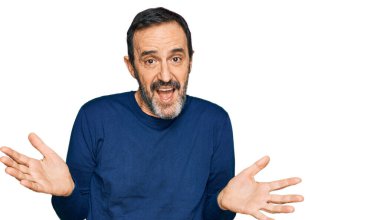 Orta yaşlı İspanyol bir adam, gündelik kıyafetler giyiyor, elleri ve kolları havada, kafası karışmış bir ifade takınıyor. şüphe kavramı. 