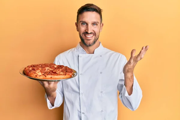 Όμορφος Άντρας Γενειάδα Επαγγελματίας Μάγειρας Κρατώντας Ιταλική Πίτσα Γιορτάζει Επίτευγμα — Φωτογραφία Αρχείου