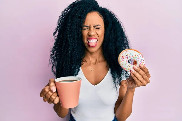 Afrykańska Kobieta Średnim Wieku Jedząca Pączki Pijąca Kawę Wystaje Języczkiem — Zdjęcie stockowe