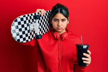 Genç Latin bir kadın elinde soda içerek kaykay yapıyor. Depresyonda ve üzüntüden ağlıyor. Kızgın ve korkmuş. hüzünlü ifade. 