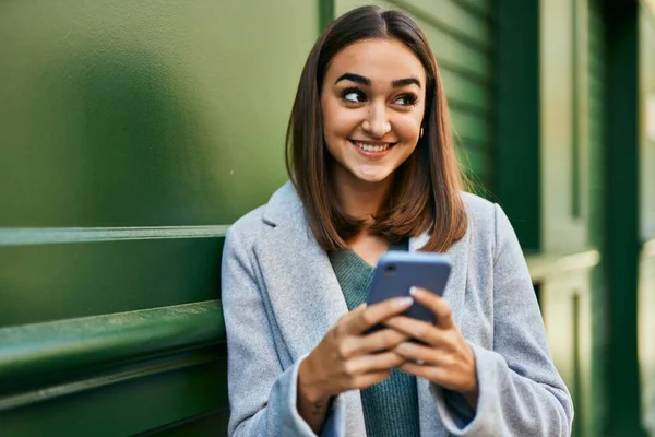 若いですヒスパニック系の女の子笑顔幸せな使用してスマートフォンで市 — ストック写真