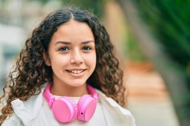 Şehirde kulaklık takıp gülümseyen İspanyol çocuk..