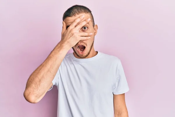 Jovem Hispânico Vestindo Camisa Branca Casual Espreitando Choque Cobrindo Rosto — Fotografia de Stock