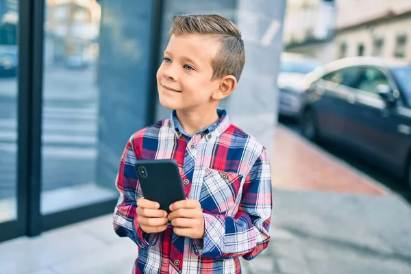 Beyaz Çocuk Şehirde Akıllı Telefon Kullanarak Mutlu Bir Şekilde Gülümsüyor — Stok fotoğraf