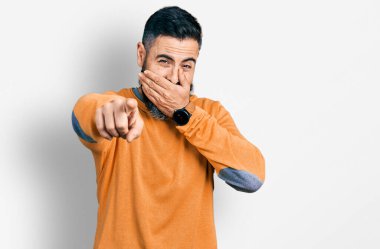 Kış süveteri giyen İspanyol sakallı adam sana gülüyor, eli ağzında kamerayı işaret ediyor, yüz ifadesi utanç verici. 