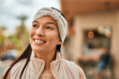 Genç Latin kadın gülümseyerek şehirde mutlu mesut duruyor..