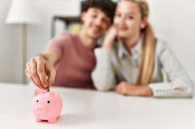 Genç çift evdeki kumbara içine para yerleştiriyor..