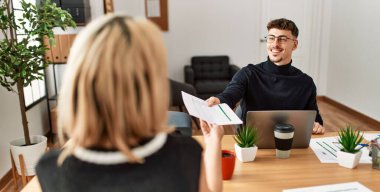 Ofiste dizüstü bilgisayarla çalışırken gülümseyen iki iş adamı..