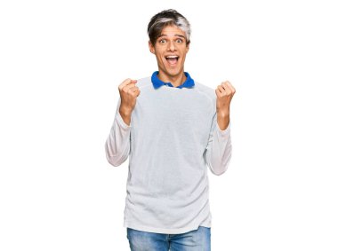 Gündelik giysiler giyen genç İspanyol adam şaşkınlık ve şaşkınlık içinde kollarını kaldırarak ve gözlerini açarak başarıyı kutluyor. Kazanan konsept. 