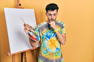 İspanyol asıllı genç adam paletle resim çizerken kendini iyi hissetmiyor ve soğuk algınlığı ya da bronşitin belirtisi olarak öksürüyor. sağlık hizmeti kavramı. 