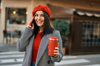 Genç İspanyol kadın akıllı telefondan konuşuyor ve şehirde kahve içiyor..