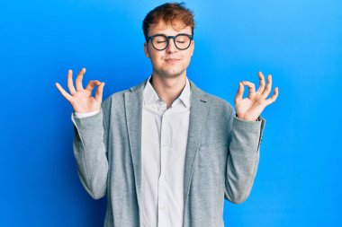 Zarif kıyafetler giyen, gözlüklü, gülümseyen, gözleri kapalı, parmaklarıyla meditasyon yapan beyaz bir adam. yoga konsepti. 