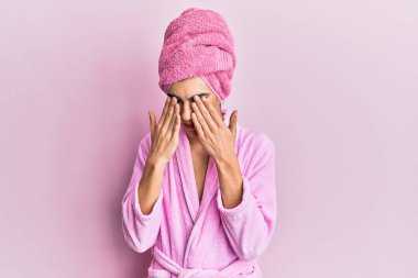 Başında duş havlusu ve bornozla makyaj yapan genç adam yorgunluk, baş ağrısı, uykulu ve yorgun ifade için gözlerini ovuşturuyor. görme sorunu 