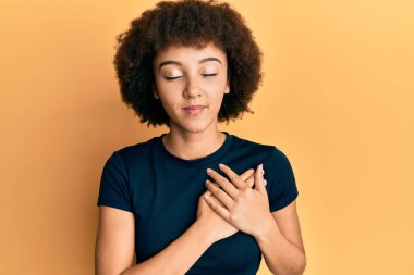 Elleri göğsünde gülümseyen, yüzünde minnet dolu bir jestle gülümseyen Latin asıllı genç bir kız. sağlık kavramı. 