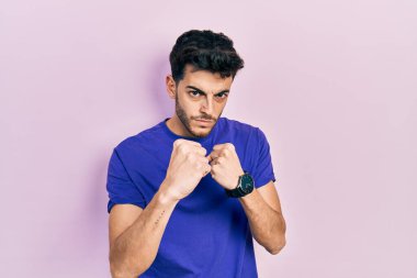 Gündelik tişört giyen genç İspanyol adam yumruk savunma hareketiyle dövüşmeye hazır kızgın ve üzgün bir yüz, sorundan korkuyor. 