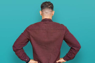 Gündelik kıyafetler giyen genç İspanyol adam kolları vücudunda geriye doğru bakıyor. 