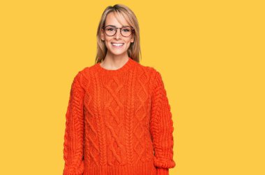 Güzel sarışın kadın sıradan kıyafetler ve gözlük takıyor ve yüzünde mutlu ve havalı bir gülümseme var. şanslı kişi. 