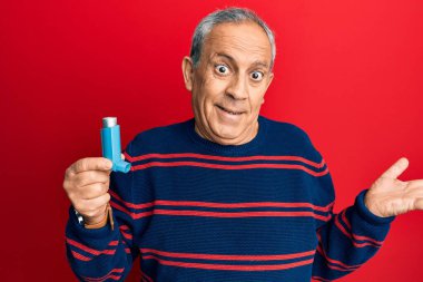 Kıdemli İspanyol asıllı adam tıbbi astım spreyini tutarak başarıyı mutlu bir gülümsemeyle ve kazanan ifadeyle kutluyor. 