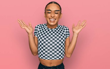 Makyajlı, uzun saçlı, modern kıyafetler giyen İspanyol transseksüel adam başarı için deli ve deli gibi kutlama yapıyor. Kolları havada ve gözleri kapalı, heyecanla bağırıyor. Kazanan konsept 