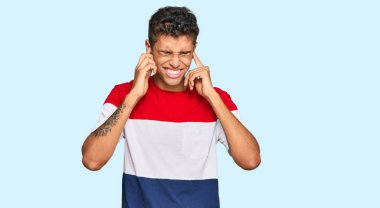 Genç, yakışıklı, Afro-Amerikan bir adam gündelik kıyafetler giyip yüksek sesli müzik sesi için kulaklarını parmaklarıyla kapatıyor. sağır kavramı. 