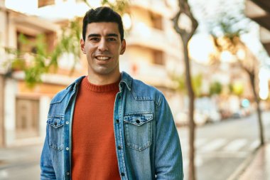 Genç İspanyol adam gülümseyerek şehirde mutlu mesut dikiliyor..