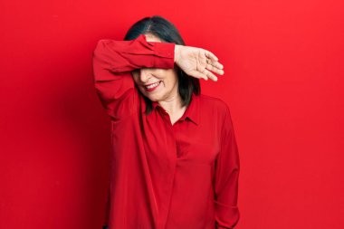 Orta yaşlı İspanyol kadın gündelik kıyafetler giyip kollarıyla gözlerini kapatıyor neşeli ve komik gülümsüyor. kör kavram. 