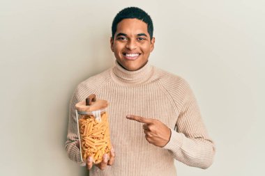 Genç, yakışıklı İspanyol adam elinde makarna kavanozuyla gülümsüyor. 