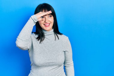 Genç İspanyol kadın gündelik giysiler giyiyor çok mutlu ve gülümsüyor başlarını kaldırıp uzaklara bakıyor. arama kavramı. 