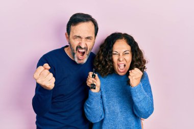 Orta yaşlı bir çift İspanyol kadın ve elinde yeni evin anahtarları olan kızgın ve kızgın bir adam öfkeyle bağırırken yumruklarını kaldırıyor. öfke ve agresif konsept. 