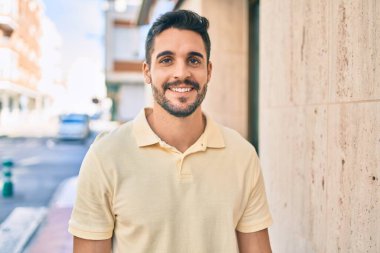 Genç İspanyol adam gülümseyerek şehirde mutlu bir şekilde yürüyor..