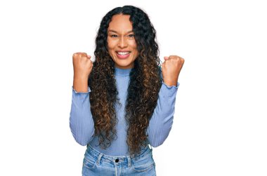 Kıvırcık saçlı genç İspanyol kadın kollarını kaldırıp, gözlerini açarak başarıyı kutluyor ve şaşırıyor. Kazanan konsept. 