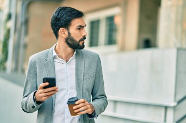Zeki telefon kullanan ve şehirde kahve içen Latin asıllı genç bir işadamı..