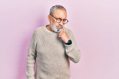 Sakallı, sıradan süveter giyen ve gözlüklü yakışıklı bir adam. Gözünü dikip jestini izliyor. Şüpheli bir ifade. 