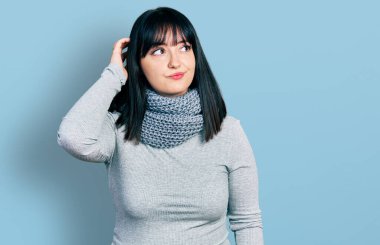 Kış eşarbı takan Latin kökenli genç ve cüsseli bir kadın soru sorup kafasını karıştırıyor. Şüpheyle kararsız, kafa kafaya düşünerek. Düşünceli kavram. 