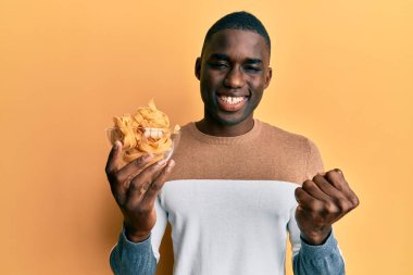 Genç Afro-Amerikan adam elinde fırında pişmemiş spagetti ile gururla bağırıyor zaferi ve başarıyı kutluyor. 